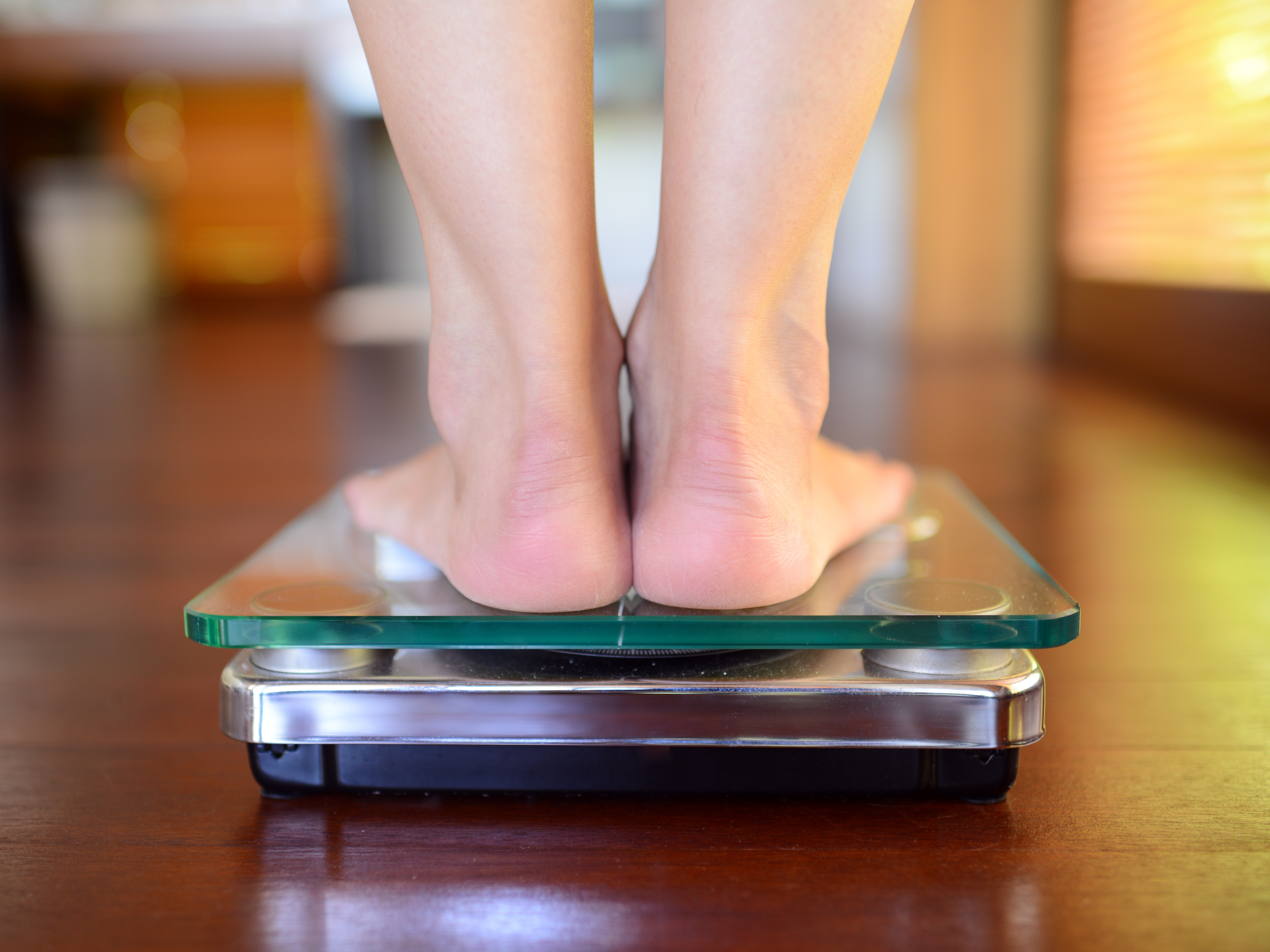 Top view of feet on weighing scale. Women weigh on a weight balance scale  after diet control. Healthy body weight. Weight and fat loss concept. Weight  measure machine. Body Mass Index or