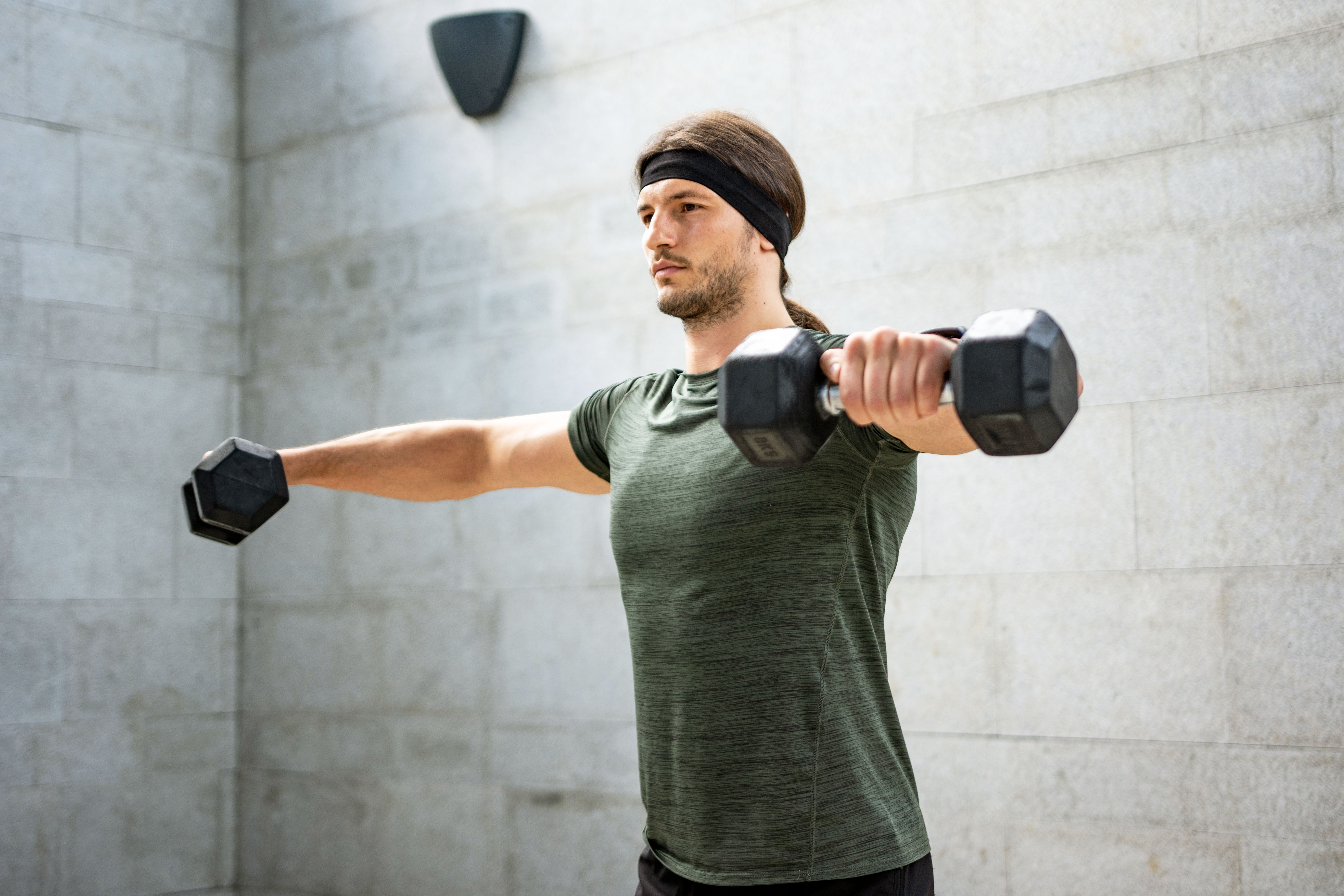 Concentrated man doing dumbbell workout. Well trained body with bulky  muscles. Sport equipment and weightlifting. Stock Photo