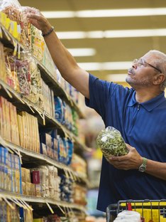 man shopping in grocery store reading ingredient list
