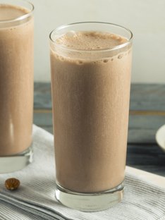 A tall glass of a chocolate peanut butter protein shake