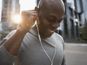 靠近微笑的男性跑步者听音乐与锻炼耳机