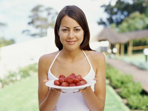 一幅年轻女子的画像，手里拿着一盘草莓