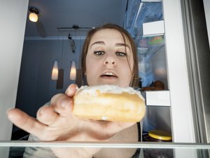 一个女人从冰箱里拿甜甜圈