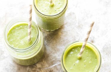 Green smoothie in three cups on gray table
