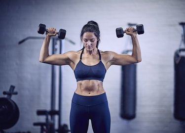 Woman doing dumbbell overhead press for the best shoulder workout