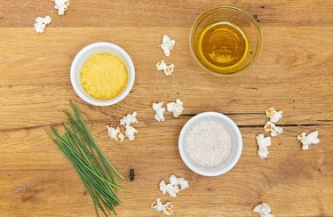 Popcorn on wooden table with nutritional yeast and chives