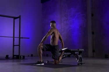 Woman demonstrating how to do the kneeling quad stretch with twist as part of a mobility workout