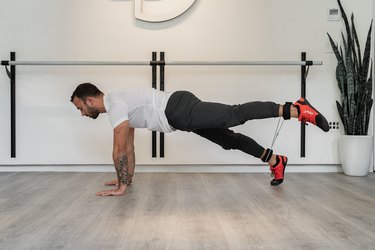 Man Doing Plank + Wide Straight Leg Raise With Resistance Band