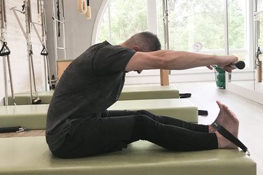 Man performing a pilates single leg stretch exercise on a reformer