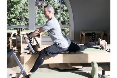 man performing pilates split on reformer