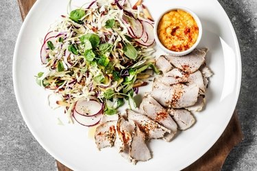 A Whole30 meal of sliced pork and salad that includes Whole30 fats