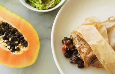 overhead photo of a blue zones-inspired breakfast recipe Tropical Black Bean, Cheese, and Papaya Burrito on a white plate