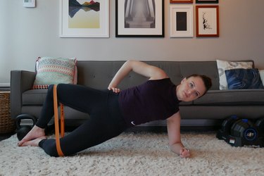 Woman demonstrating how to do a banded side plank to clam shell