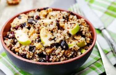 a close up photo of a blue zones-inspired breakfast recipe for quinoa porridge in a black bowl with green apple slices and raisins