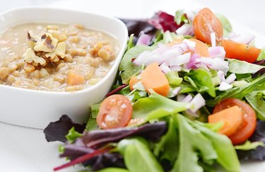 Nutty Lentil Soup in a small square bowl with a side of salad on white plate.