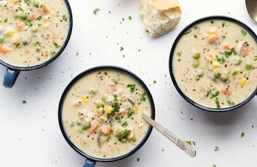 Creamy Dairy-Free Pot Pie Soup with vegetables in black bowl on white countertop.