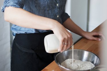 女人倒牛奶在碗里。