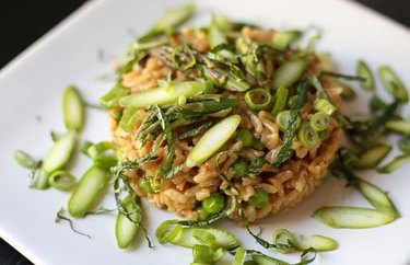 Instant Pot Risotto With Dried Mushrooms, Asparagus, Peas and Spring Onions on a white plate.