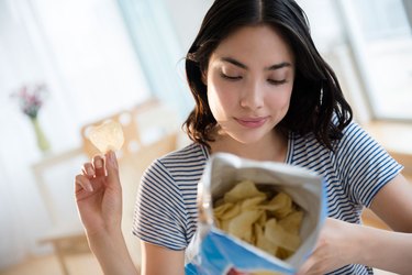 Woman eating processed foods processed snacks like potato chips health risks