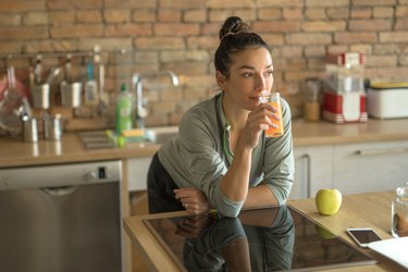 Woman drinking juice in her kitchen