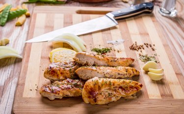 Grilled chicken breasts on a cutting board after grilling on a gas grill