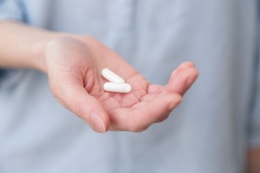Woman holding white pill capsules like Keto Ultra Diet Supplement