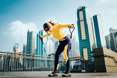 Woman using handle resistance band on bridge.