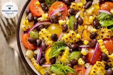 Top view of a grilled corn and black bean salad with tomatoes and onions