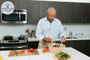 An older adult making a salad in his kitchen