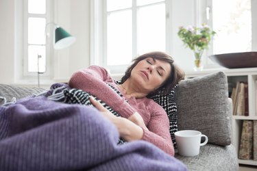 Woman lying on couch and feeling uncomfortable after eating