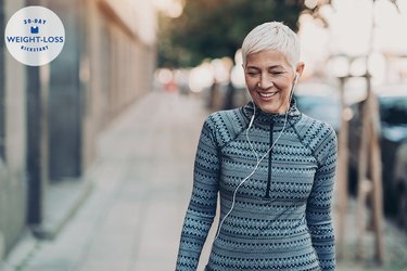 older woman taking a walk outside with headphones