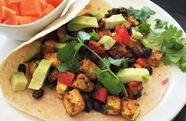Breakfast Recipes for Longevity Meatless Mexican Breakfast Wrap on a white plate with a flour tortilla and cilantro
