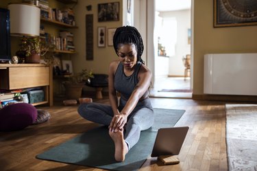 Woman is stretching before starting an at-home yoga flow