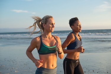 Two runners running on the beach during sunrise or sunset on vacation travel fitness workout