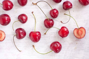 overhead view of several whole cherries and one with the cherry pit exposed