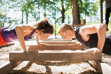 Man and woman doing push-ups outside in park on a nice day