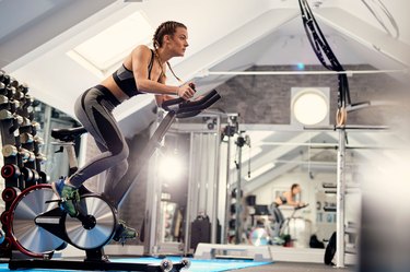 Woman using stationary indoor exercise bike for fitness