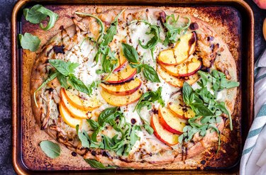 overhead shot of chicken peach ricotta pizza on a cutting board