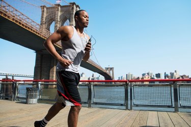 Man running in New York City near Brooklyn Bridge using a half-marathon training schedule for beginners.