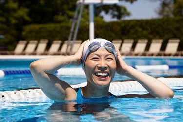 Woman in outdoor lap pool with swim cap and goggles