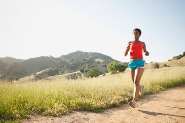 Woman running on a hilly trail to train for an ultramarathon