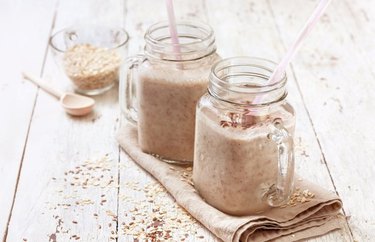 blue zone breakfast recipe oatmeal smoothie in glass mason jars with straws, a spoon and a tan cloth napkin
