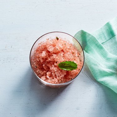Icy watermelon granita in a glass, topped with a basil leaf