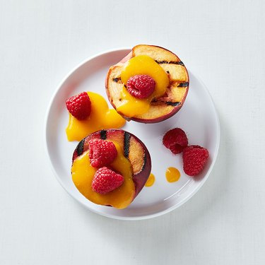 One peach, halved, with grill marks, topped with mango sauce and raspberries