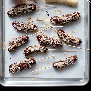 Frozen bananas dipped in chocolate and topped with sliced nuts and coconut