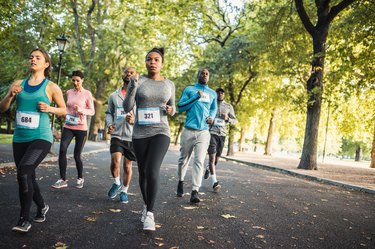 Runners in a park competing in a race following a marathon training schedule for beginners