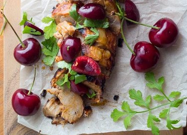 Sliced pork tenderloin topped with cherries and herbs