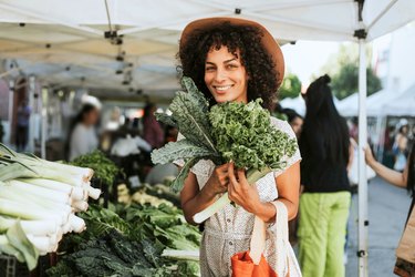 Woman holding bunch of kale at farmer's market