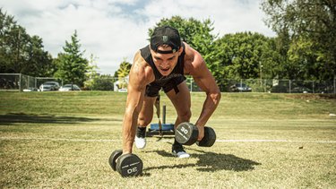 man lifting weights while sprinting down a field