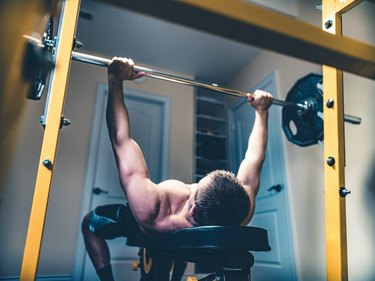 photo of man lifting weights doing bench press